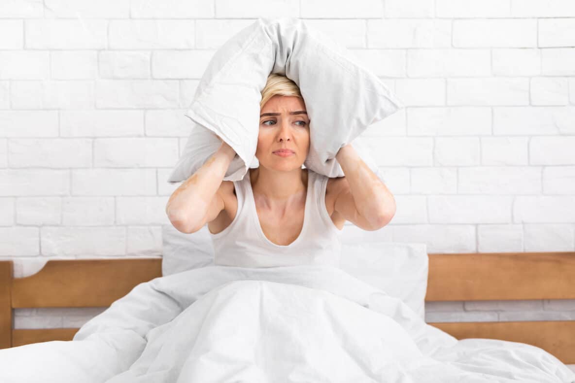lady sitting in bed with pillow around her head