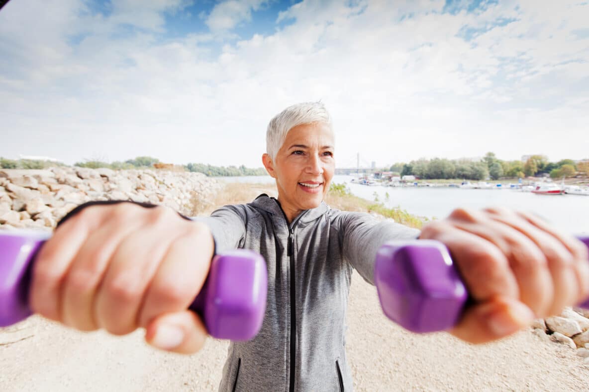 Mature woman with great hair outside lifting hand held weights